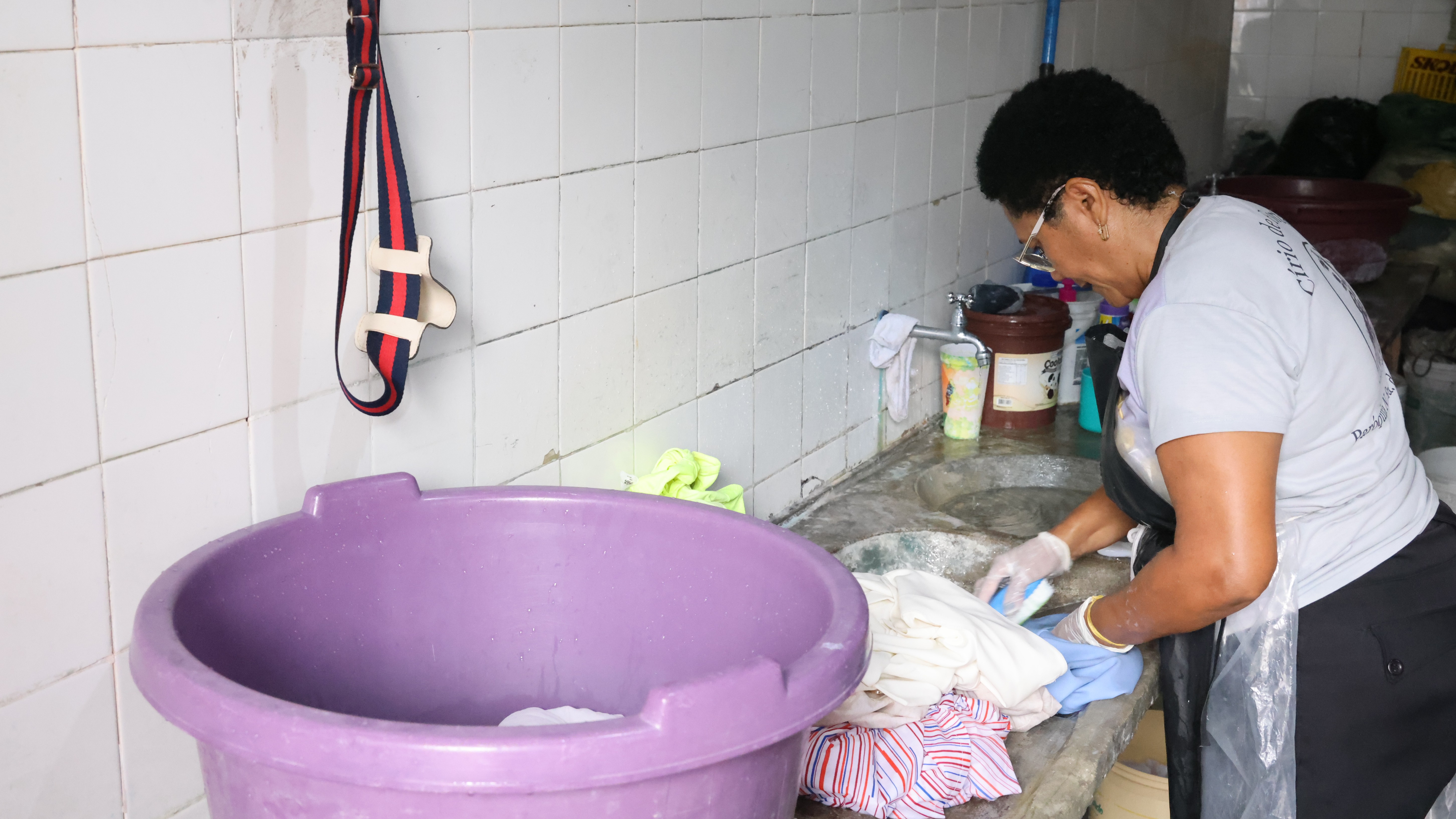 lavadeira enxaguando a roupa em um tanque no interior da lavanderia